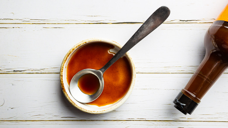 Worcestershire sauce in a bowl next to a sauce bottle