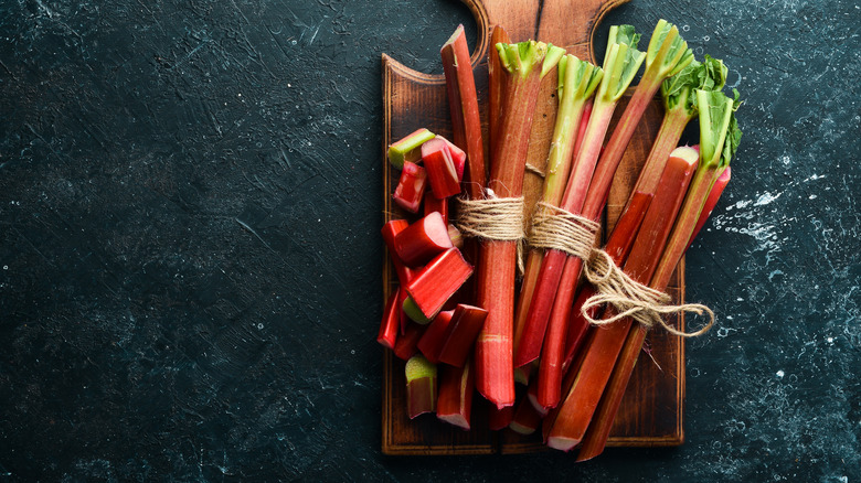 Rhubarb stalks and pieces laid on a wooden chopping board