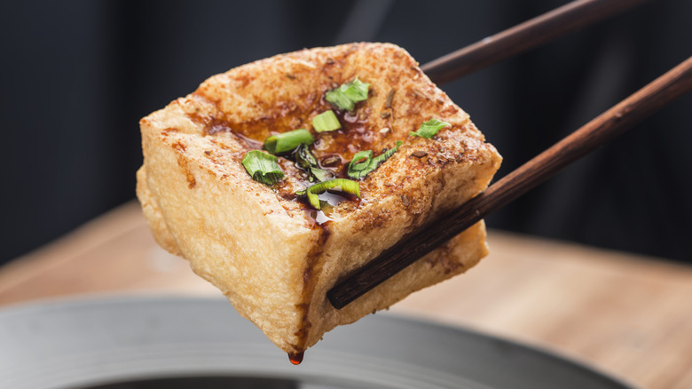 Chopsticks holding marinated tofu