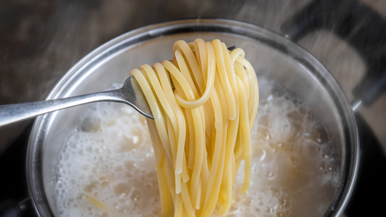 fork with spaghetti over pot