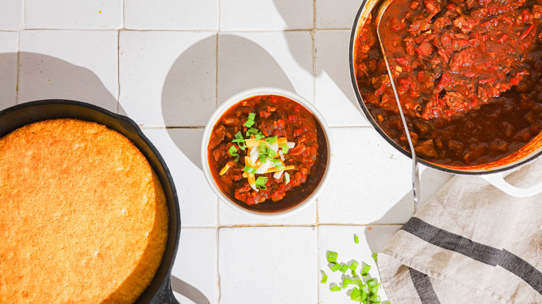 Bowl of chili, pot of chili, and cornbread on counter