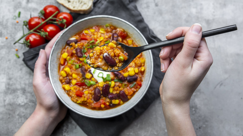 hands stiring a bowl of chili