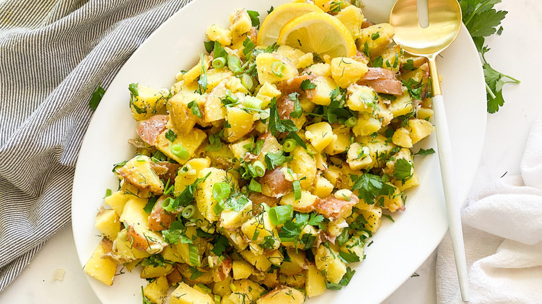 French potato salad on white plate with spoon