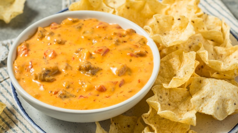A bowl of chunky queso dip and chips
