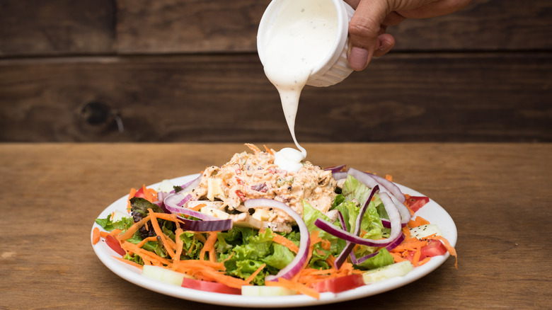 Ranch dressing pouring on salad