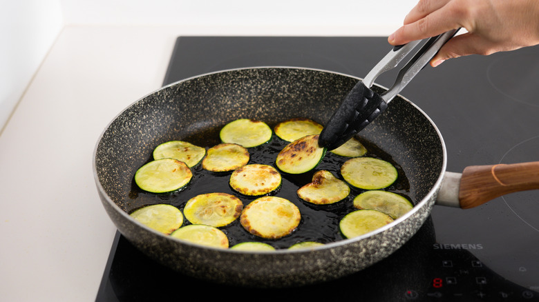 zucchini slices frying in a pan