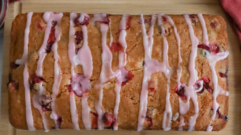 loaf of glazed cranberry bread on cutting board