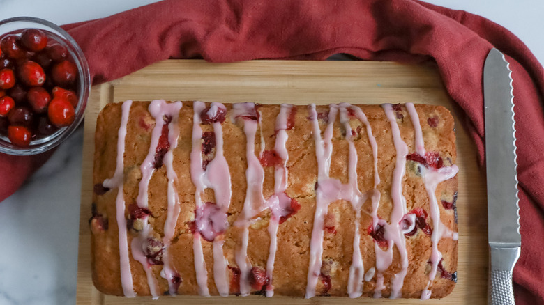 glazed cranberry bread with knife on cutting board