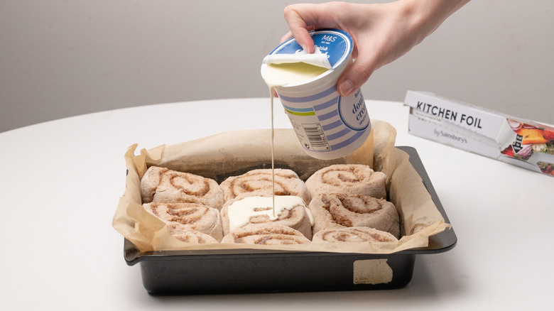 pouring cream over cinnamon rolls