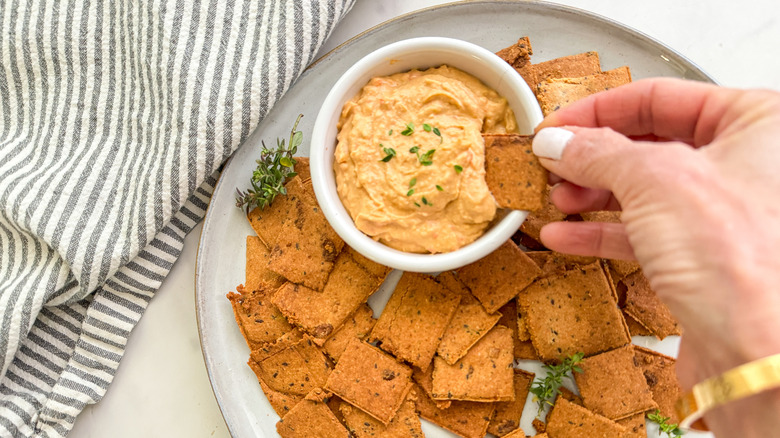 hand dipping cracker in dip