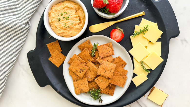 crackers on black tray with hummus and cheese