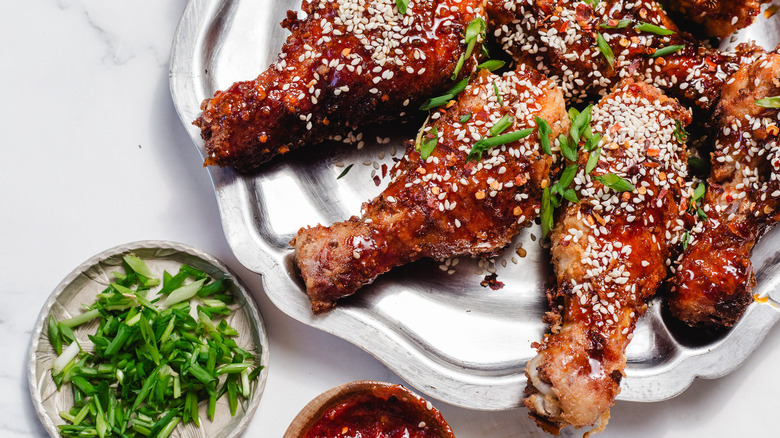 drumsticks on a platter with scallions and sauce