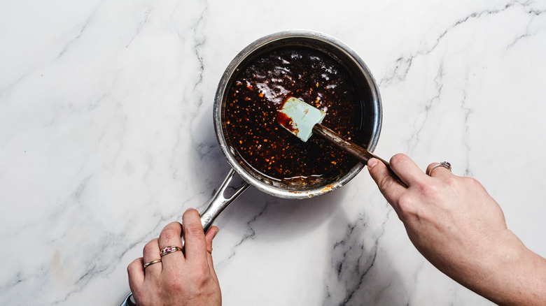 Hand stirring sauce in pan with spatula