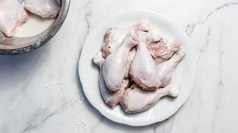 drumsticks on plate besides bowl with more drumsticks in marinade