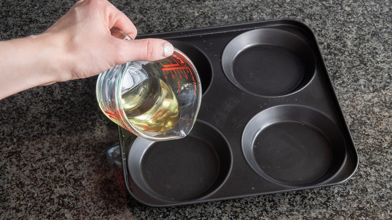 hand pouring oil into pan