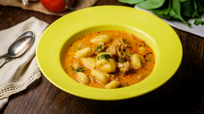 Gnocchi soup in yellow bowl