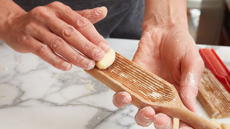 Hands rolling gnocchi on board with flour