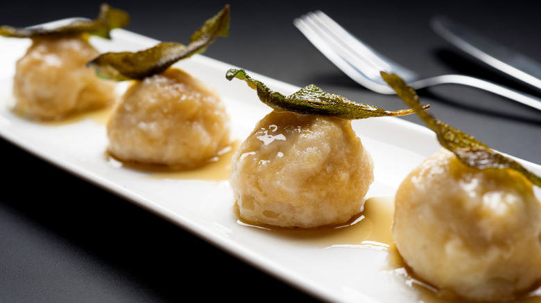 Ricotta gnudi on white plate with sage