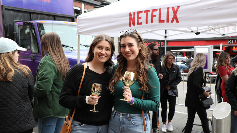 Two women smiling and holding gold wine glasses