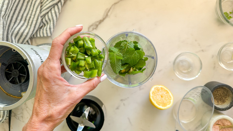 hand adding jalapeno to blender