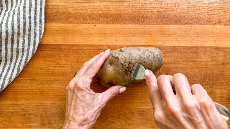 hand poking fork in potato