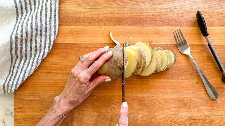 hand slicing potato on board