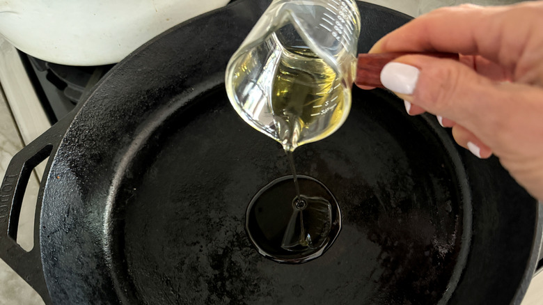 hand adding oil to pan