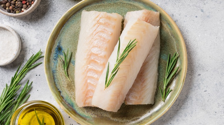 Raw fish on plate with poaching ingredients