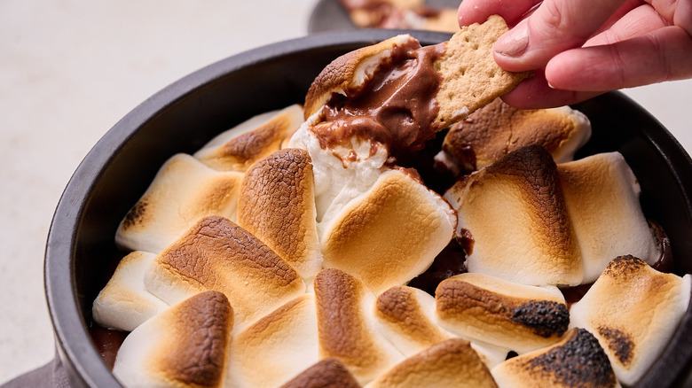 dipping graham cracker in s'mores dip