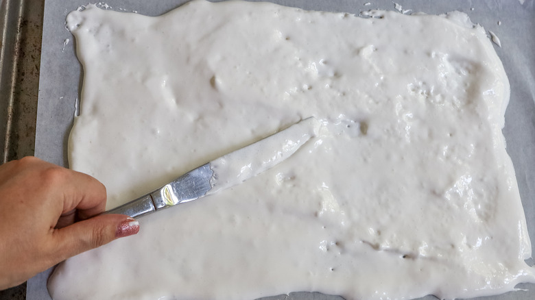 marshmallow creme being spread on parchment paper