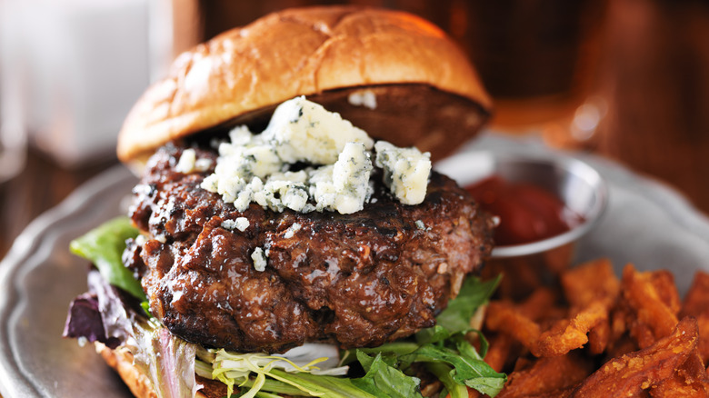 Gourmet burger with cheese on patty on plate of sweet potato fries 