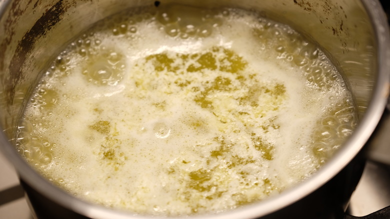 Butter melting in water on the stove in a pot