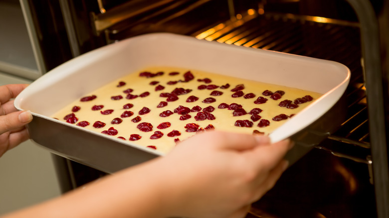 hands putting dish in oven