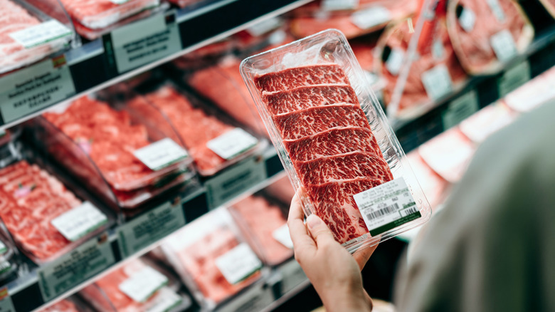 shopper examining a package of raw beef at the grocery store