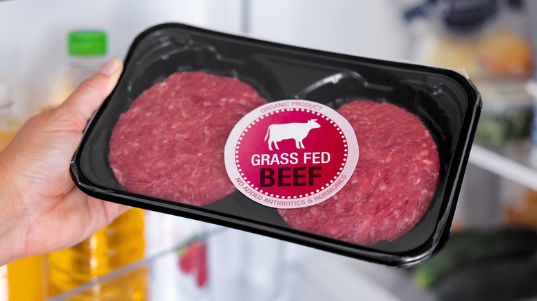 package of grass fed beef in hand by fridge