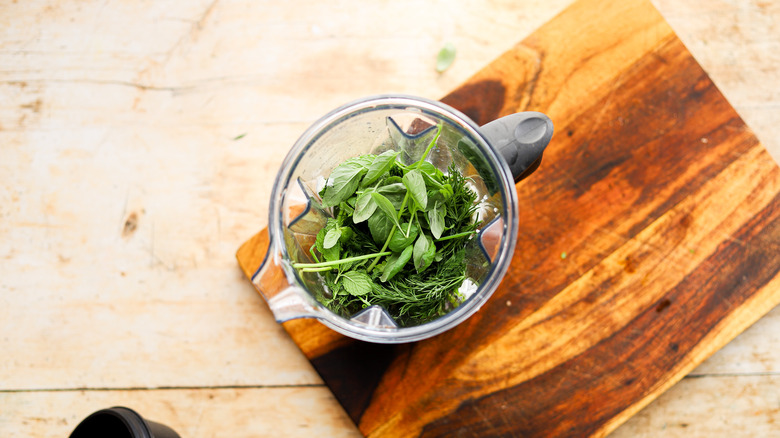 Blender full of green herbs