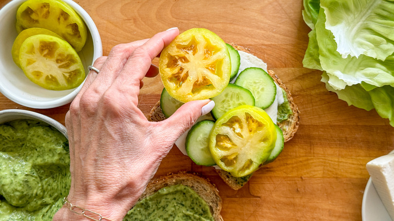 hand making vegetable tomato sandwich