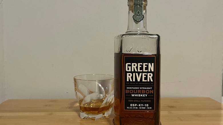 Green River Bourbon Whiskey bottle with a neat glass behind it