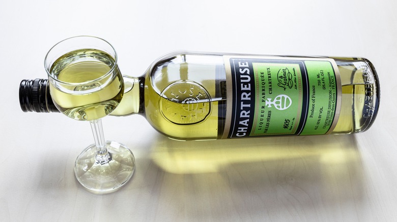 Bottle of green Chartreuse turned on its side beside a glass