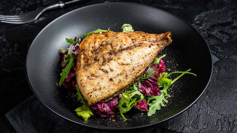 Cooked dorado tail in dish with salt and pepper seasoning