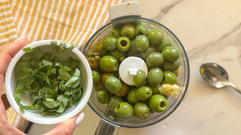 adding basil to olives