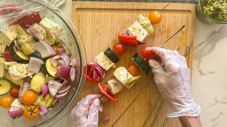 hands putting pepper on skewer