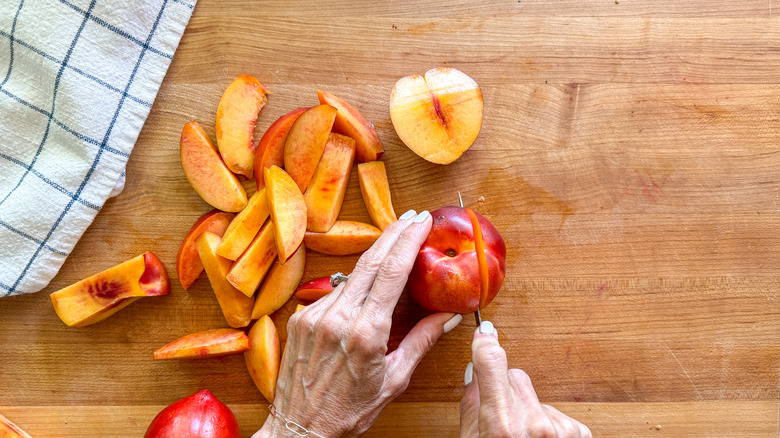 hand cutting nectarine on board