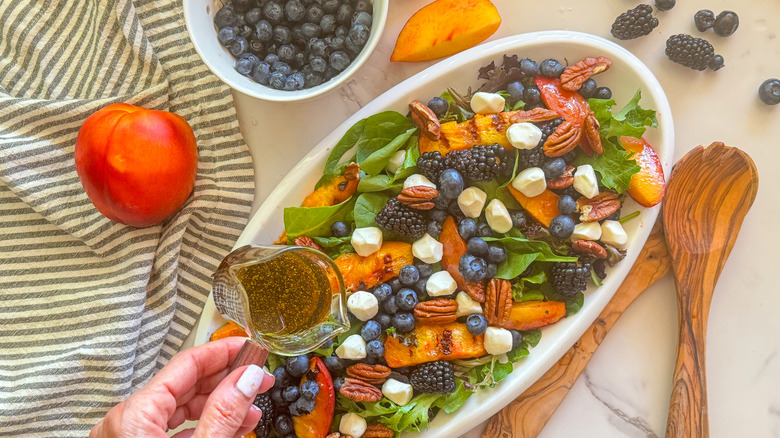 hand adding dressing to salad