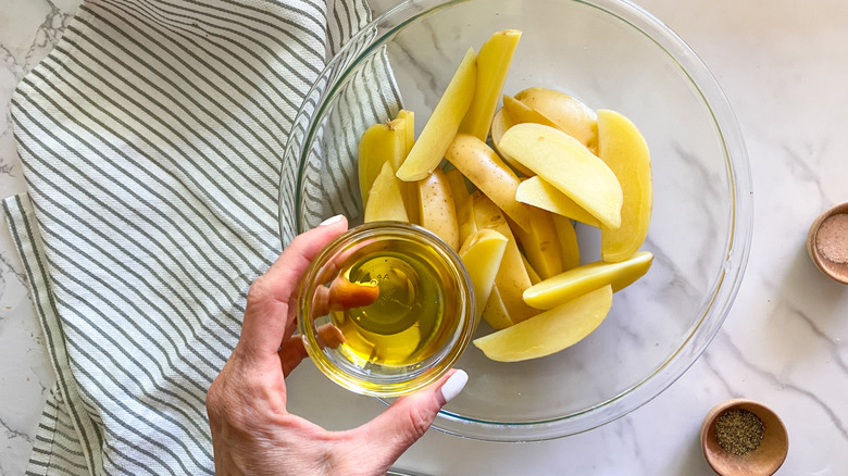 adding oil to potatoes