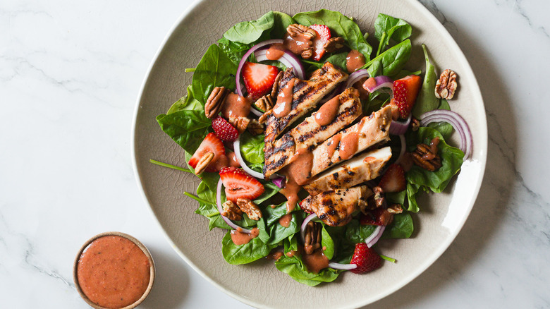 Chicken salad with strawberries on plate with pink sauce