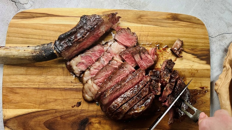 hand cutting tomahawk steak