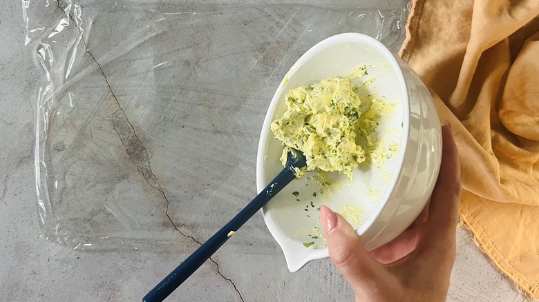 hand holding bowl of butter over plastic wrapp