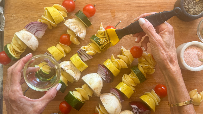 hand brushing the skewers