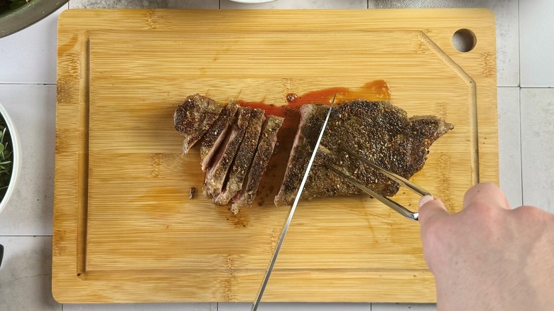 slicing steak on cutting board